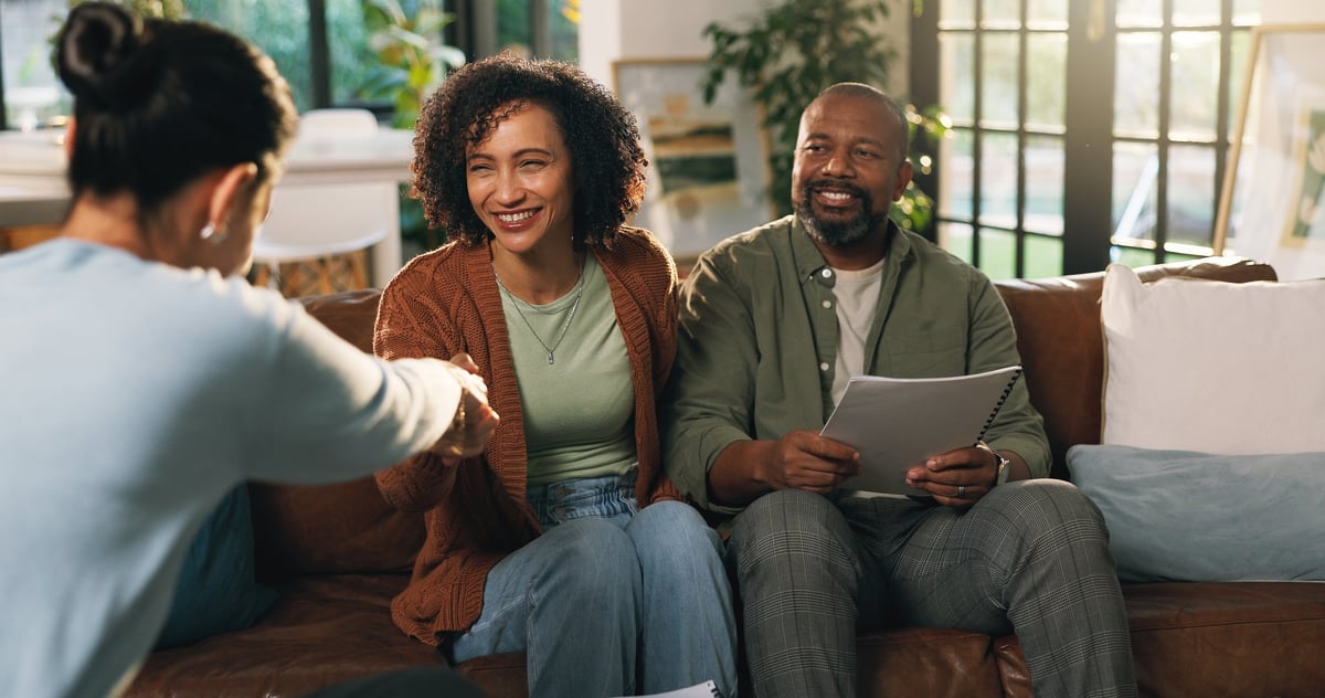 An African American couple shaking hands with their financial advisor in their living room