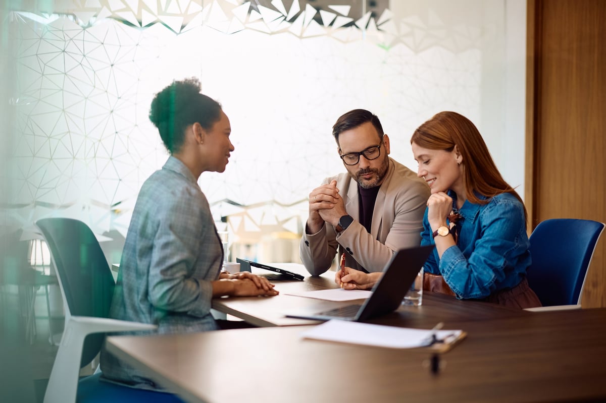 A woman and her partner signing documents with their bank advisor in the office